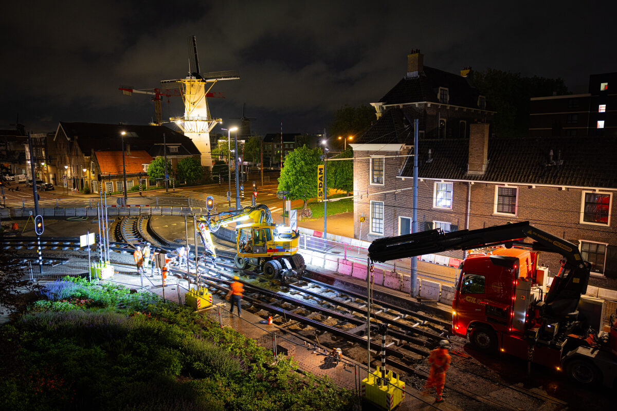 Het vervangen van wissels van tramspoor in Schiedam met op de achtergrond een prachtig uitgelichte molen